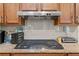 A close up look at a gas cooktop with stainless steel vent hood and modern subway tile at 8336 Sw 77Th Ct, Ocala, FL 34476