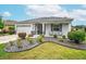 Well-maintained home with a stone-mulched garden, green lawn, and welcoming front porch with seating at 8336 Sw 77Th Ct, Ocala, FL 34476