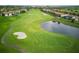 Scenic aerial view of a lush green golf course with sand traps and a pond at 9061 Dogleg Dr, Davenport, FL 33896