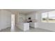Open-concept kitchen featuring white cabinets, stainless steel appliances, island with sink, and tile floors at 9113 Wildlight, Wildwood, FL 34785