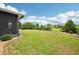 Lush backyard with a manicured lawn, green hedges, and partial view of a screened-in lanai at 106 Mist Flower Ln, Groveland, FL 34736