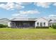 Back view of a charming home with solar panels and a screened-in lanai, overlooking a lush backyard at 106 Mist Flower Ln, Groveland, FL 34736
