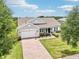 Charming front view of a single-Gathering home with a brick driveway, well-maintained lawn, and inviting entryway at 106 Mist Flower Ln, Groveland, FL 34736