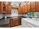Functional laundry room with ample storage, dark counters, upper and lower cherry wood cabinets, and modern appliances at 106 Mist Flower Ln, Groveland, FL 34736