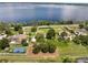 Stunning aerial view of a lakeside property with lush greenery, a tennis court, and access to a serene lake at 12130 Lakeshore Dr, Clermont, FL 34711