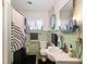 Bathroom featuring retro green tile, modern sink, and round mirror hung with rope at 12130 Lakeshore Dr, Clermont, FL 34711