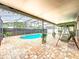 Screened-in pool area featuring brick flooring, patio swing, landscaping, and string lights for ambiance at 12300 Abberton Ct, Orlando, FL 32837