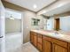 Bright bathroom with a double vanity, light wood cabinets, and an open doorway to the bedroom at 13055 Overstreet Rd, Windermere, FL 34786
