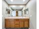 Well-lit bathroom featuring a double vanity with light wood cabinets and a large mirror at 13055 Overstreet Rd, Windermere, FL 34786