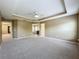 Large main bedroom with tray ceiling, carpet, ensuite bathroom access, and natural light from multiple windows at 13055 Overstreet Rd, Windermere, FL 34786
