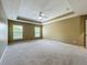 Spacious main bedroom with a tray ceiling, carpet flooring, and windows providing natural light at 13055 Overstreet Rd, Windermere, FL 34786