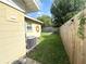 Fenced backyard with a lush lawn, shade tree, air conditioner unit, and partial patio with chairs at 1400 Yates St, Orlando, FL 32804