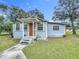Charming single-story home featuring a covered front porch, mature trees, and well-maintained landscaping at 211 N Randolph Ave, Kissimmee, FL 34741