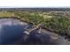 Scenic aerial view of a lake with a pier and boat docks surrounded by lush greenery at 3426 Schoolhouse Rd, Harmony, FL 34773