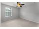 This bedroom has neutral paint, a ceiling fan, and a bright window with a pleasant view at 3426 Schoolhouse Rd, Harmony, FL 34773