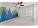 Bright bedroom with blue and green mountain mural, plush carpeting, and a ceiling fan at 3426 Schoolhouse Rd, Harmony, FL 34773