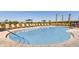 Community swimming pool with lounge chairs, umbrellas, and palm trees on a sunny day at 471 Wayland Dr, Haines City, FL 33844