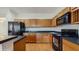 Efficient kitchen featuring wood cabinetry, dark countertops, and modern black appliances, designed for functionality at 579 Setting Sun Dr, Winter Garden, FL 34787
