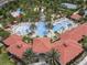 Aerial view of a resort-style swimming pool with a waterslide and palm trees, surrounded by trees and buildings at 6112 Broad Oak Dr, Davenport, FL 33837