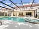 Back exterior view of a screened-in pool and spa outside of a home's covered outdoor living and dining area at 6112 Broad Oak Dr, Davenport, FL 33837