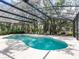 Relaxing screened-in pool area with lounge chairs overlooking lush, mature landscaping and a blue swimming pool and spa at 6112 Broad Oak Dr, Davenport, FL 33837