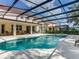 Back exterior view of a home's screened-in pool and spa, outdoor living and dining area, and green backyard at 6112 Broad Oak Dr, Davenport, FL 33837