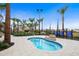 Community hot tub surrounded by lush tropical landscaping with rocks, palm trees, and a clear blue sky above at 6112 Broad Oak Dr, Davenport, FL 33837