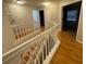 Upstairs hallway with white railing overlooking the stairs, with wood-look flooring at 7727 Glynde Hill Dr, Orlando, FL 32835