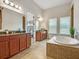 Elegant primary bath boasting a soaking tub, dual vanities, and natural light from large windows at 8047 Chilton Dr, Orlando, FL 32836