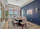 Elegant dining room features a stylish chandelier, navy accent wall with artwork, and bright, natural lighting at 8047 Chilton Dr, Orlando, FL 32836