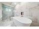 Bright bathroom featuring a soaking tub, glass enclosed shower, and elegant marble-patterned tile at 8473 Granada Blvd, Orlando, FL 32836