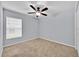 Bright bedroom featuring a ceiling fan, neutral carpeting, and a large window with horizontal blinds at 907 Pearly Ridge Ln, Lakeland, FL 33809