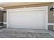 A two car garage door is closed. The driveway is paved with decorative stones. Two carriage lamps flank either side of the garage at 9426 Burnam Dr, Weeki Wachee, FL 34613