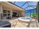 Expansive screened-in lanai with a jacuzzi, seating area, ceiling fan, and lush tropical backdrop at 9426 Burnam Dr, Weeki Wachee, FL 34613