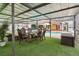 Covered patio with dining set, synthetic grass, and view of the pool and backyard at 9774 Bohart Ct, Orlando, FL 32836