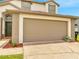 Attached two-car garage and well-manicured lawn of the two-story home at 13404 Bradwater Ct, Orlando, FL 32828