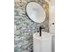 Close up of a stylish powder room with a white pedestal sink, modern faucet, and a circular mirror over mosaic tile at 13404 Bradwater Ct, Orlando, FL 32828
