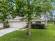 Inviting single-story home with mature trees, green lawn, and an attached two-car garage at 142 Stonegate Pass, Davenport, FL 33897