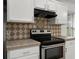 Close-up of stainless steel oven and cooktop with tile backsplash and white cabinets at 142 Stonegate Pass, Davenport, FL 33897