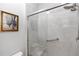 Close-up of shower featuring gray marble look and glass sliding door at 1431 Leitrim Loop, Apopka, FL 32703