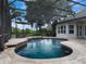 Screened in pool featuring a uniquely shaped pool, tiled flooring, outdoor seating, and mature landscaping at 2106 Ridgewind Way, Windermere, FL 34786