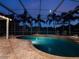 Enclosed pool area featuring a uniquely shaped pool, tiled flooring, and palm tree views at night at 2106 Ridgewind Way, Windermere, FL 34786