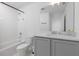 Bathroom featuring a white tub, toilet, and vanity with gray cabinetry at 2363 Lancashire St, Davenport, FL 33896