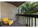 View of private balcony with painted stucco, wood deck, and chair overlooking tropical landscaping at 2636 Crown Ct, Kissimmee, FL 34741