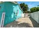 Exterior view of a turquoise home with a white fence and gravel driveway at 318 Palm St, New Smyrna Beach, FL 32168