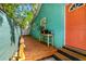 Brightly painted home featuring a wooden porch with plants and an orange entry door at 318 Palm St, New Smyrna Beach, FL 32168