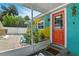 View of a colorful exterior porch with a bright orange door and a screen enclosure at 318 Palm St, New Smyrna Beach, FL 32168