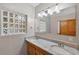 Bathroom featuring dual sinks with granite countertops, a decorative glass block window, and vanity lights above a large mirror at 3637 Dubsdread Cir, Orlando, FL 32804
