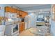 Bright kitchen featuring wood cabinets, white appliances, and adjacent dining area with a view into the bedroom at 4365 S Atlantic Ave # B8, New Smyrna Beach, FL 32169