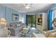 Cozy living room with blue accents, comfortable seating, and a sliding glass door that opens to the outdoor deck area at 4365 S Atlantic Ave # B8, New Smyrna Beach, FL 32169